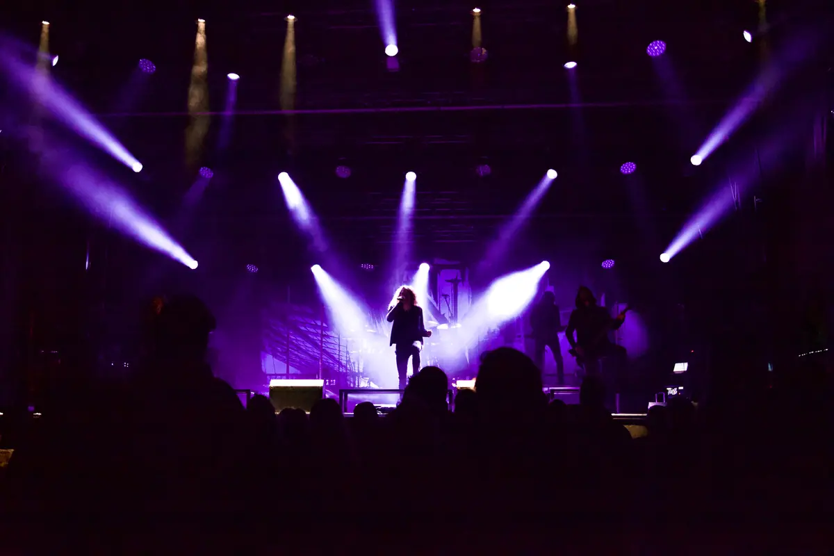 Konzert mit violetten Lichtstrahlen von Moving Heads über Band und Publikum