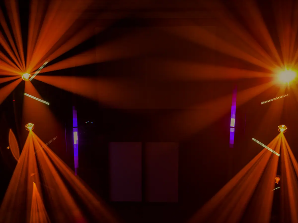 Orangefarbene Lichtstrahlen von Moving Heads in einem abgedunkelten Saal