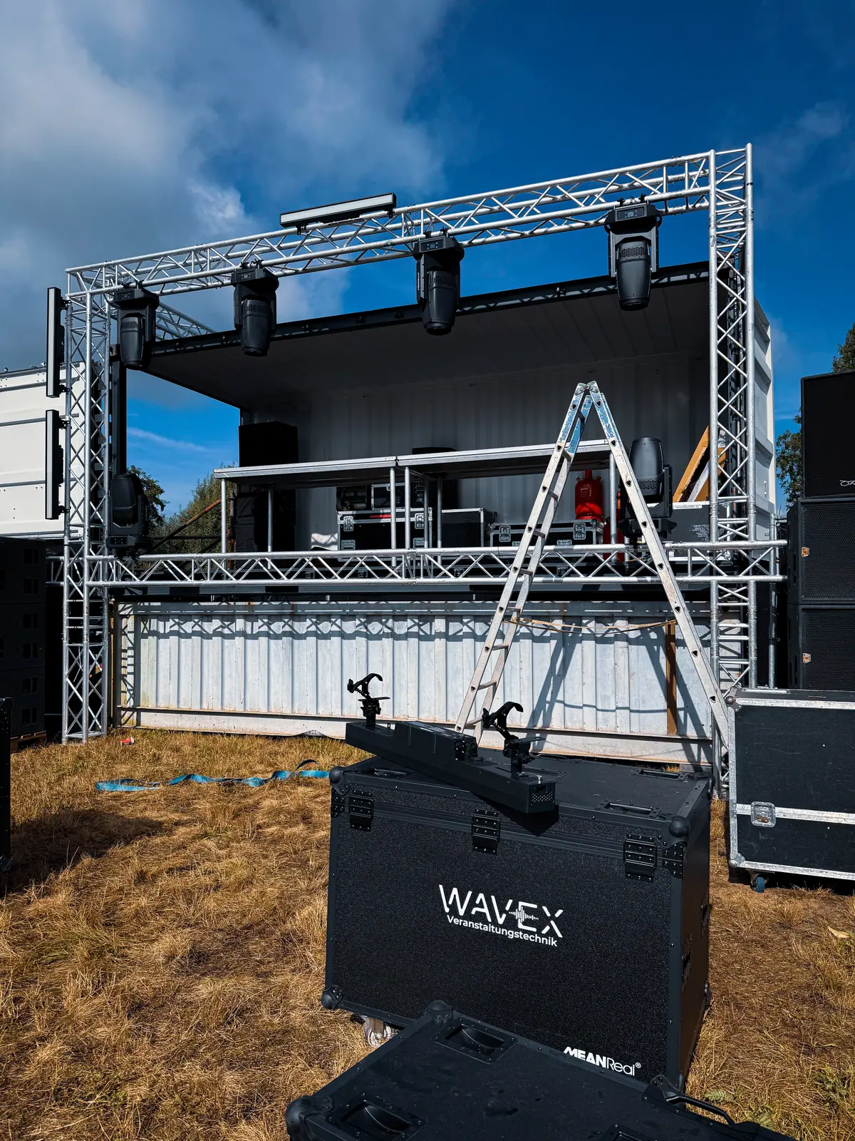 Aufbau einer Traversenbühne unter blauem Himmel mit Flightcase im Vordergrund
