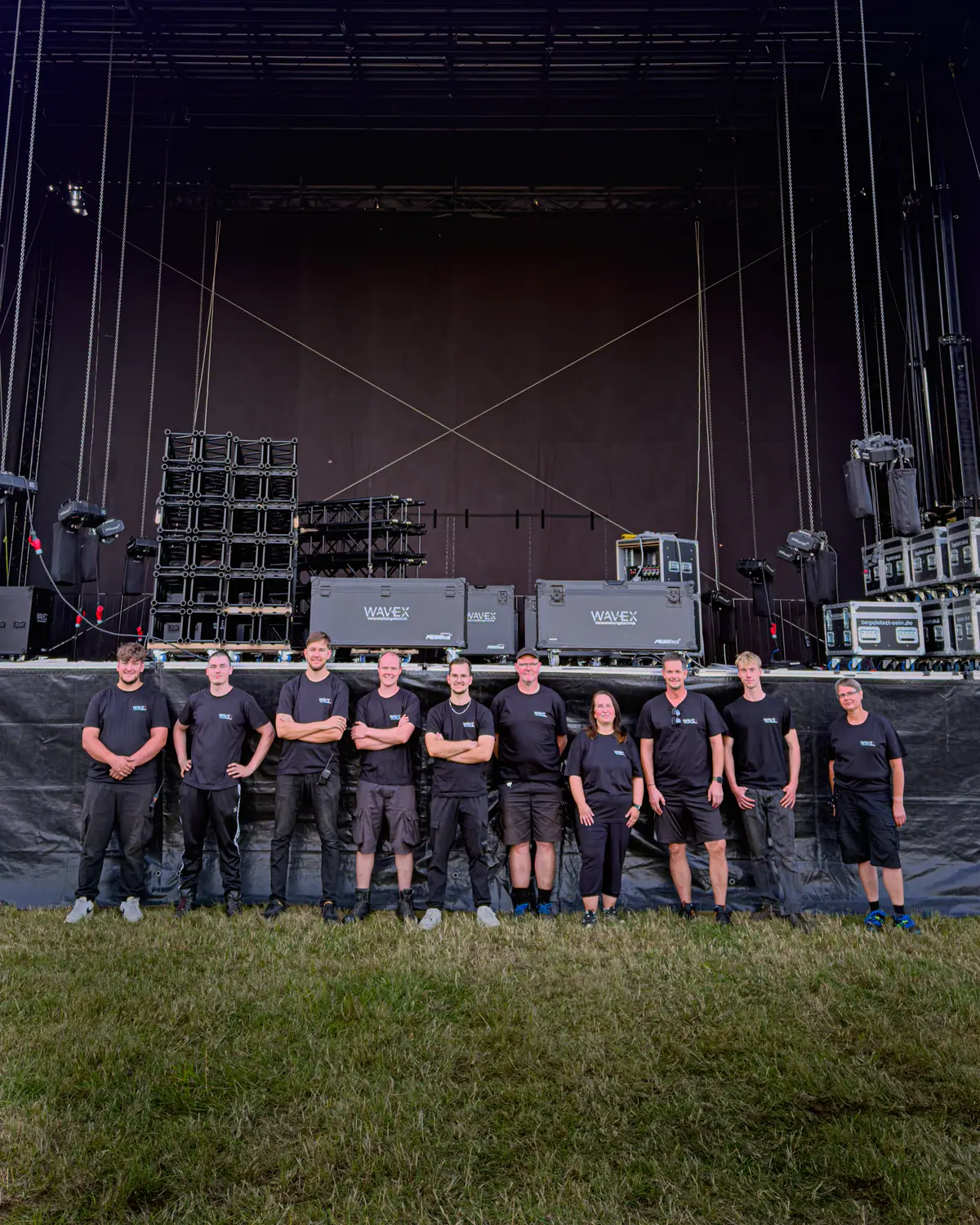 Das WaveX-Team vor einer aufgebauten Festivalbühne mit Flightcases